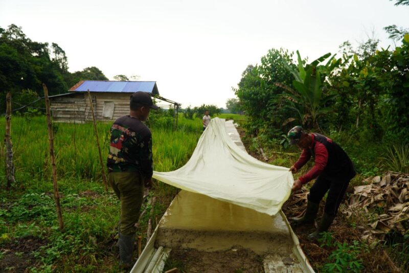 Satgas TMMD ke-126 Kodim 1208/Sambas Antisipasi Hujan, Tutup Coran Rabat Beton Dengan Plastik